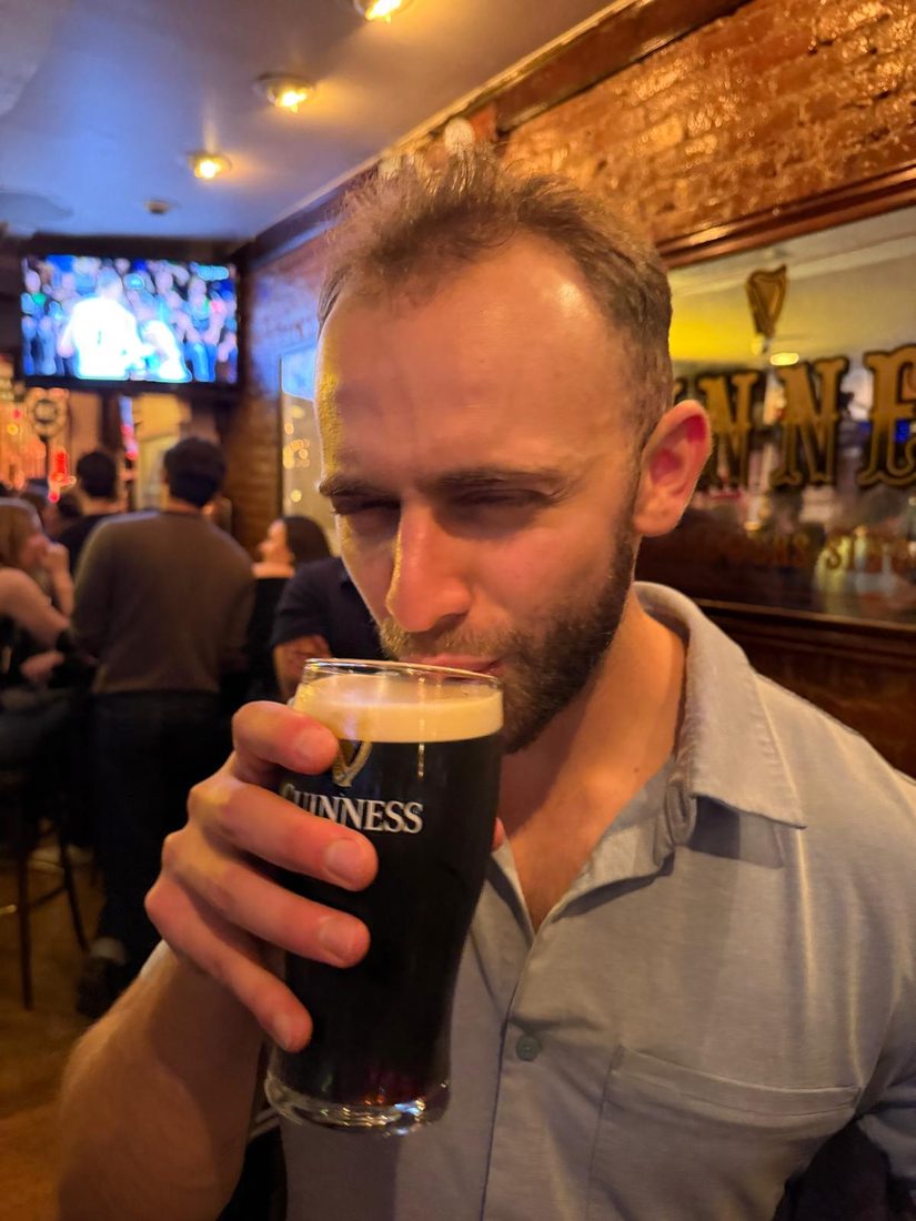 Close-up of someone drinking a pint of Guinness at a bar